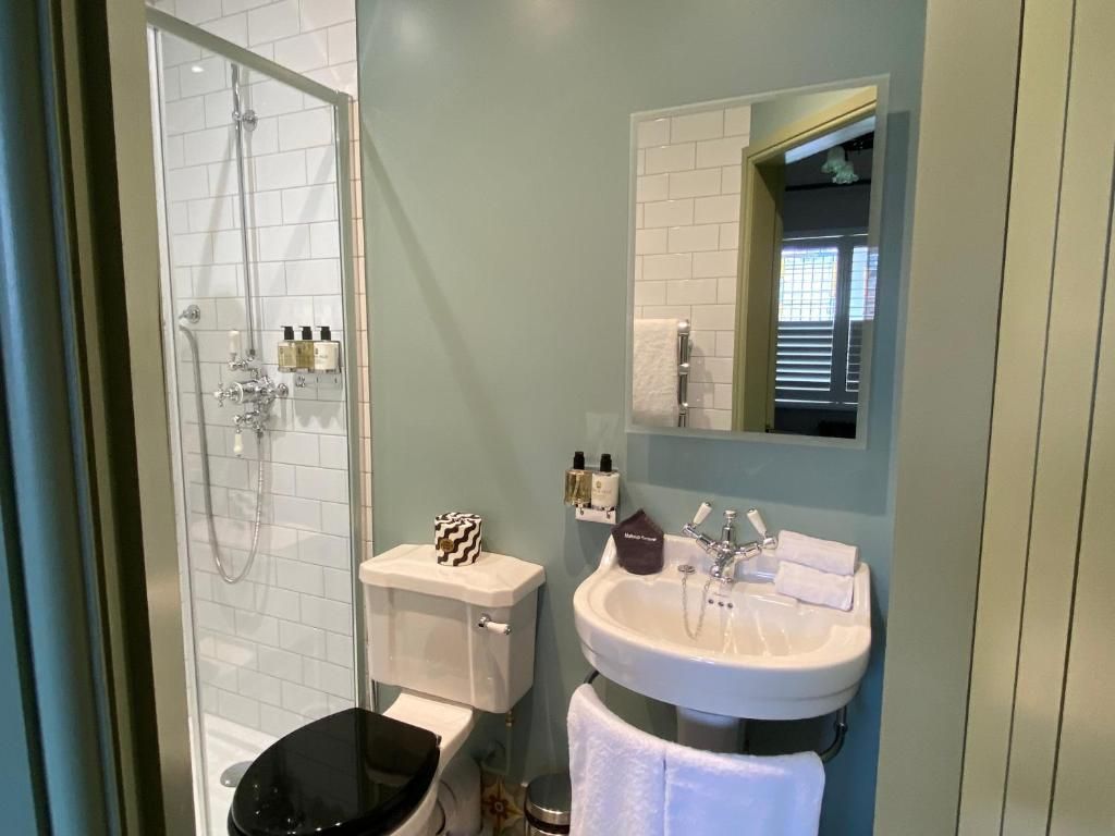 Un baño con ducha envuelta en vidrio, un lavamanos blanco y un inodoro.