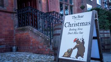 Un letrero que dice 'The Bear Tattenhall Christmas' con una ilustración de un oso e invitación a reservar.
