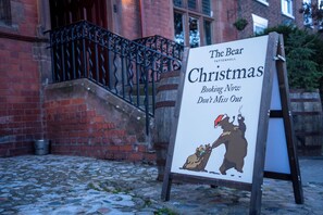 A sign for 'The Bear Tattenhall Christmas' with a bear illustration and a call to action for booking.