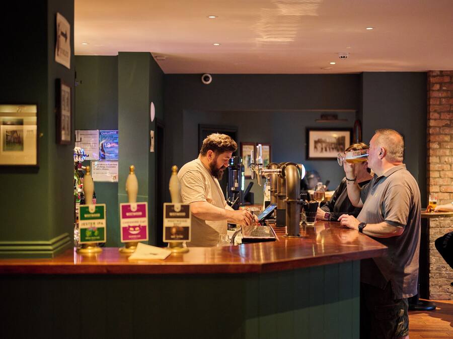 A bar area with a counter, beer taps, and a person serving a drink.