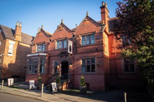 A traditional brick building with a sign for 'The Bear' pub, a staircase leading to the entrance, and a clear blue sky.