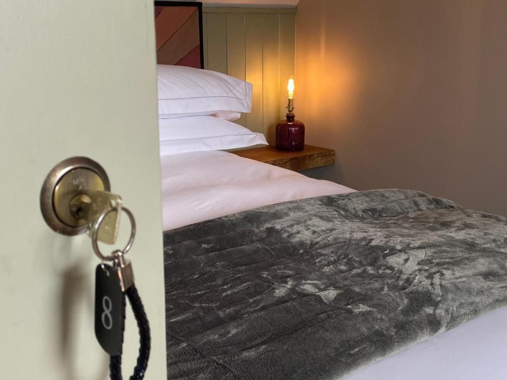 Habitación de hotel con cama, mesita de noche con vela encendida y puerta con llave.