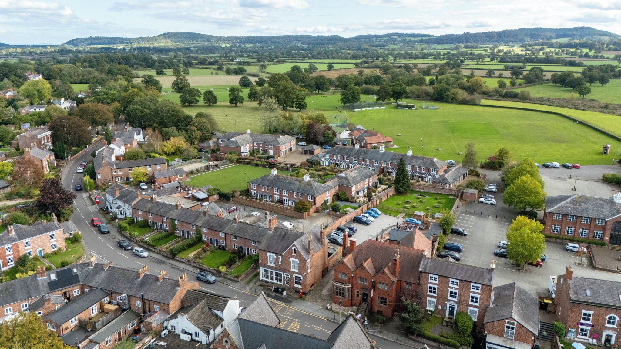 A residential area with houses, a road, and a green field.