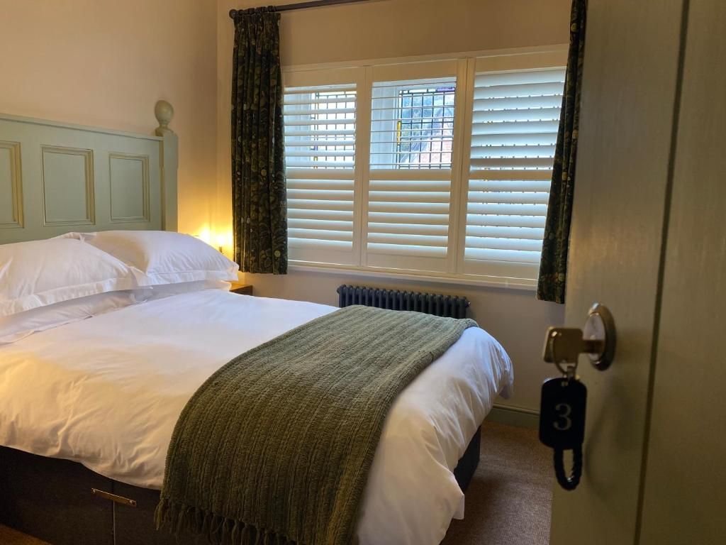 Una habitación de hotel con una cama, un radiador, una ventana con persianas y una puerta con llave.
