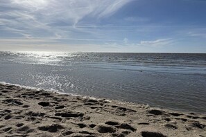 A beach with footprints in the sand and a calm sea under a clear sky. - Holiday apartment with 1 bedroom (Cuxhaven)