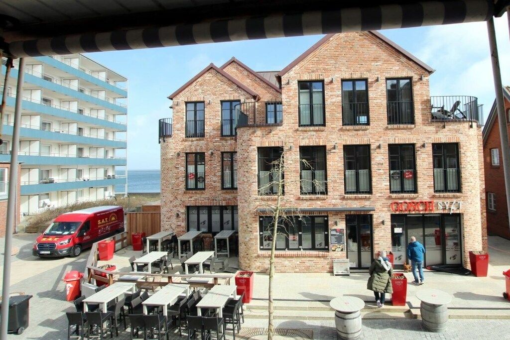 A brick building with a restaurant named 'Curry SYT' on the ground floor, outdoor seating, and a red van parked outside.