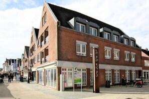 A multi-story building with a brick facade, large windows, and a ground-level shop. - Holiday apartment with 1 bedroom (Wyk auf Föhr)