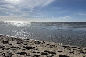 A beach with footprints in the sand and a calm sea under a clear sky. - Holiday apartment with 1 bedroom (Cuxhaven)