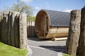A wooden cylindrical structure with a sloped roof, a wooden deck, and a paved pathway leading to it. - Holiday apartment in Büsum with swimming pool (Büsum)