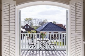 A balcony with a checkered floor, a table with chairs, and a vase with flowers. - Holiday apartment in Büsum with swimming pool (Büsum)