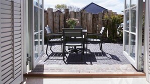 Un patio descubierto con una mesa y sillas, una valla de madera y una casa al fondo.
