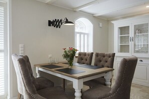 Ein Essbereich mit Tisch, Stühlen, einer Blumenvase und einem Schrank mit Gläsern.