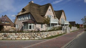 A stone house with a thatched roof and a stone wall. - Holiday apartment in Büsum with swimming pool (Büsum)