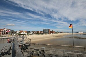 A coastal promenade with a sandy beach, a boardwalk, and buildings in the background. - 8 at Königstr. 5, Atlantic Court (Wyk auf Föhr)
