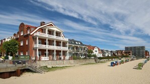 Un hôtel situé en bord de mer, doté de nombreux balcons, d’une promenade en bord de plage et de cabanes de plage.