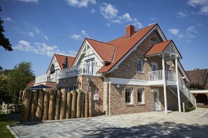 Een huis met twee verdiepingen, een bakstenen gevel, een dak met rode tegels en een houten hek.