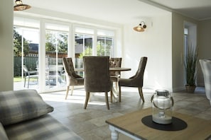 Een eethoek met een tafel en stoelen, een bank en een potplant.