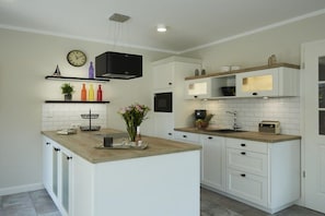 Een moderne keuken met witte kasten, een houten eiland en een ingebouwde oven.