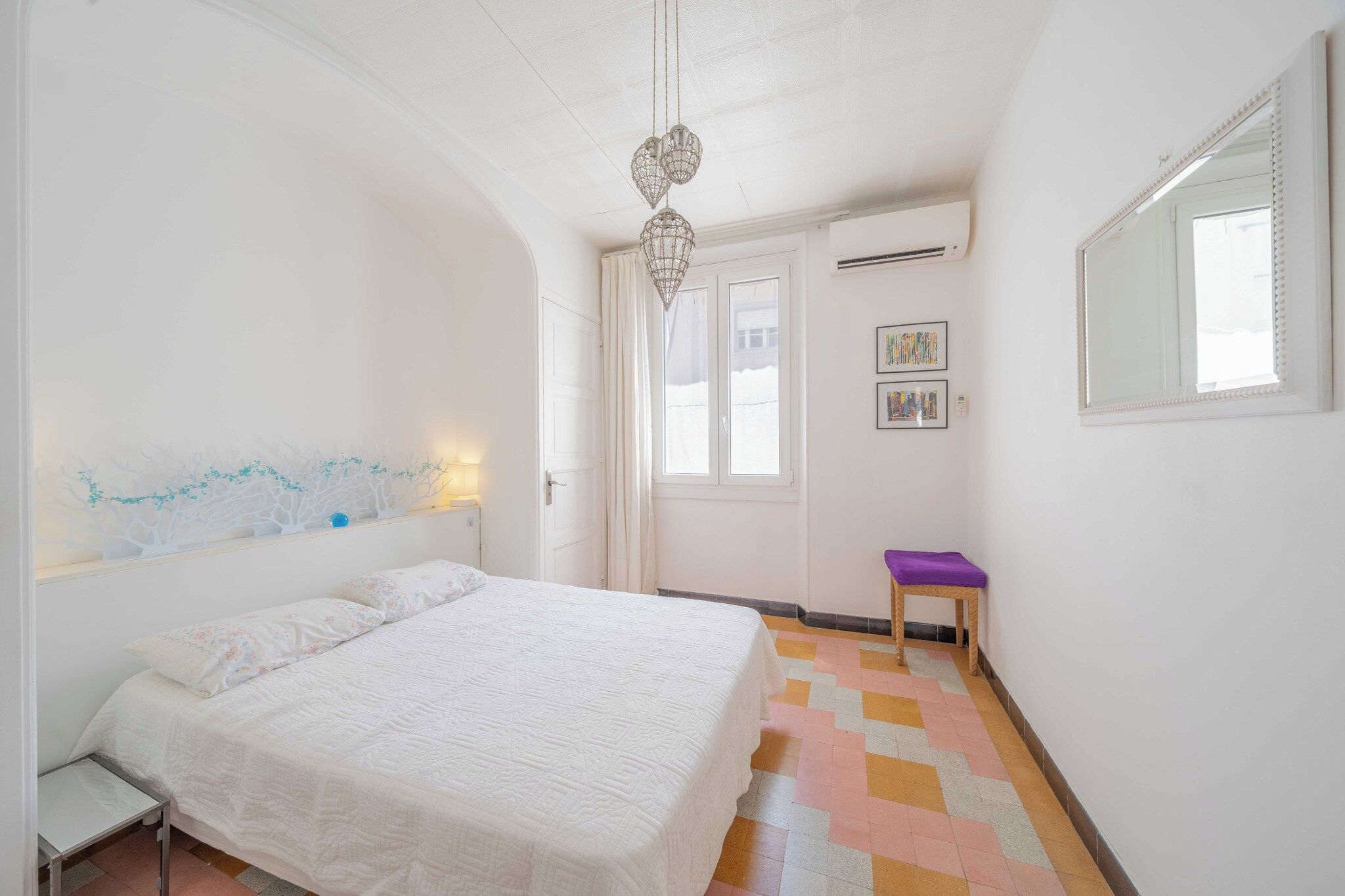 A bedroom with a bed, a nightstand, a dresser, a window, and a door.
