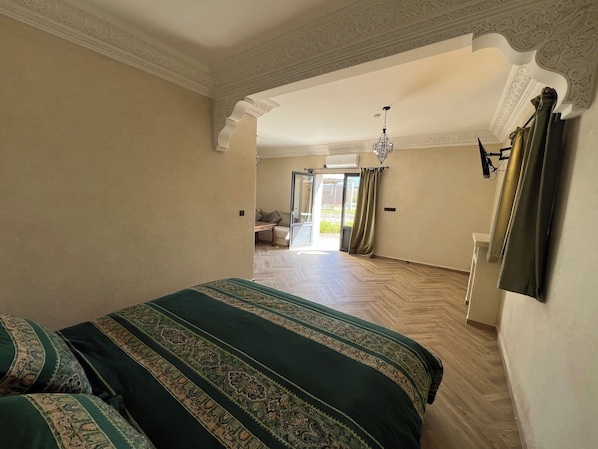 Un dormitorio amplio con una cama grande, un ventilador de techo y vistas a un balcón desde una puerta abierta.