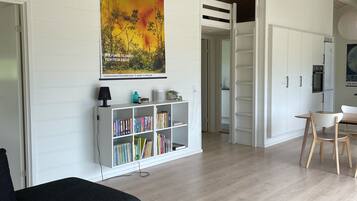 A modern living room with a bookshelf, a painting, and a dining area.