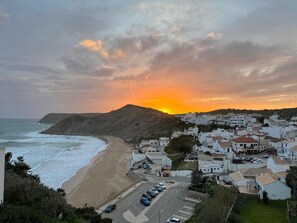 A coastal town with a beach, buildings, and a sunset. - Casa do Mar Aromas Condomínio by CoolHouses (Burgau)