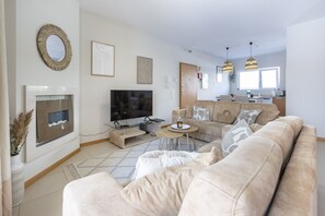 Una sala de estar moderna con un televisor de pantalla plana, un sofá color beige, una mesa de centro y una chimenea.