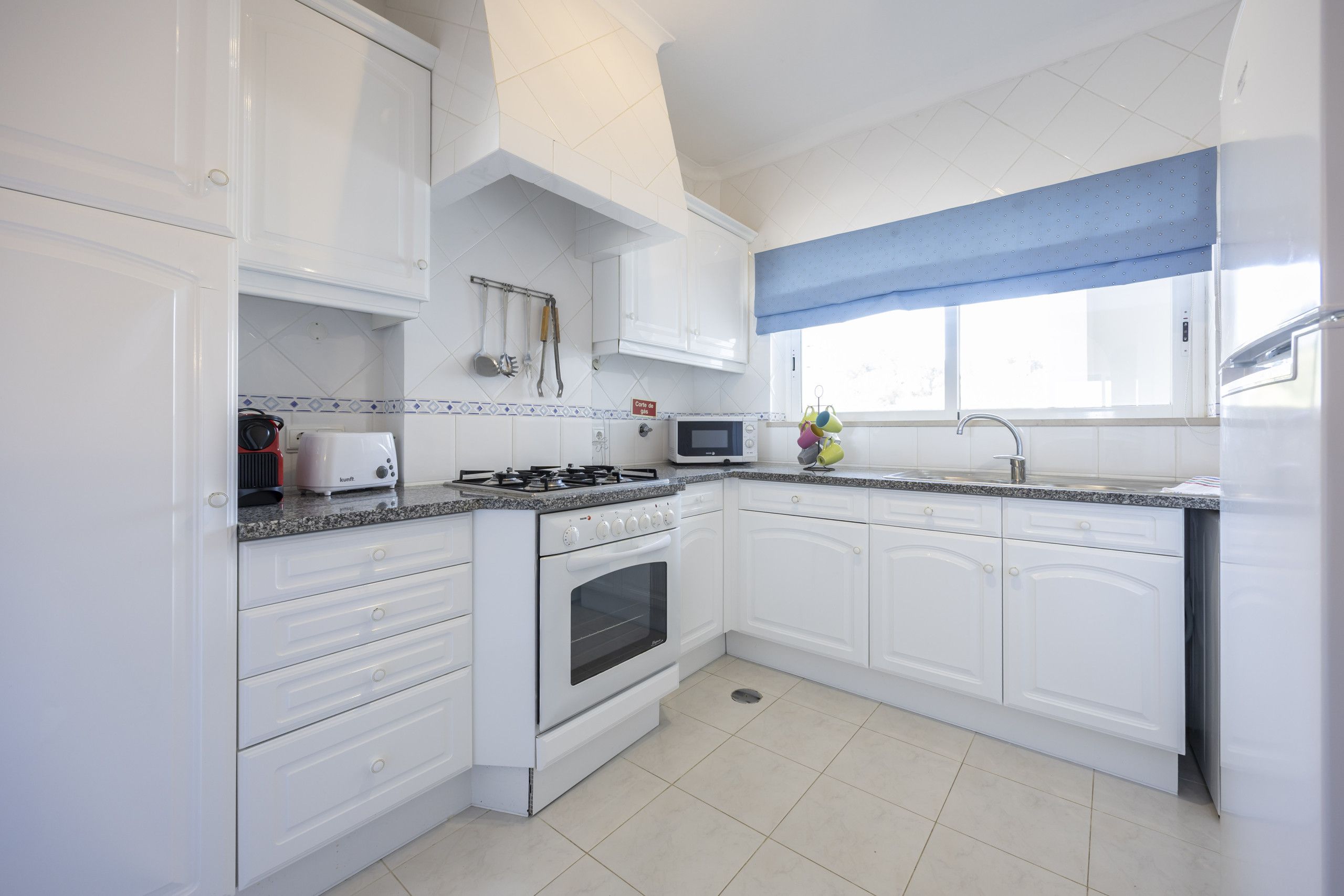 Een moderne keuken met witte kasten, een gasfornuis, een magnetron en een spoelbak.