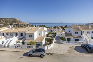 A coastal town with white buildings, a paved street, and a car parked on the side. - CoolHouses Algarve Luz | Ramalhete T2 (Luz)