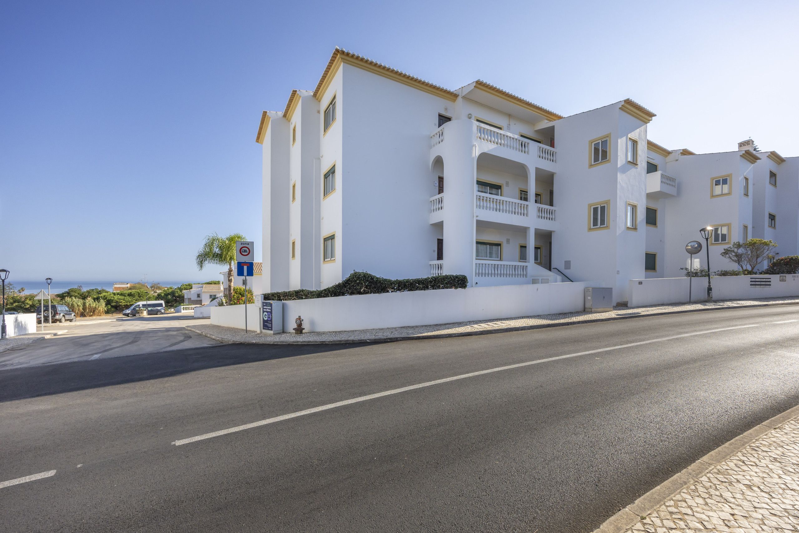 A multi-story building with balconies, a clear sky, and a road in the foreground.