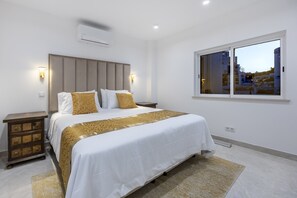 A hotel room with a bed, bedside tables, a window, and an air conditioning unit. - The Penthouse Waterside by CoolHouses (Luz)