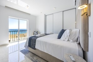 A modern bedroom with a large bed, a view of the sea through a sliding door, and a balcony. - The Penthouse Waterside by CoolHouses (Luz)