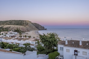 Uma cidade costeira com edifícios brancos, uma praia e um penhasco.