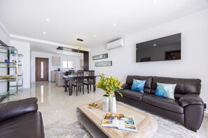 Ein modernes Wohnzimmer mit einer Couch, einem Couchtisch und einem Essbereich mit Stühlen und einem Tisch.