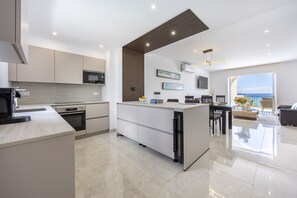A modern kitchen with a central island, built-in appliances, and a dining area with a view. - The Penthouse Waterside by CoolHouses (Luz)