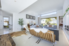 Ein modernes Wohnzimmer mit einer Couch, Sesseln, einem Couchtisch und einem großen Fenster.