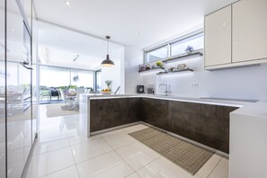 A modern kitchen with a dark countertop, white cabinets, and a large window. - Vila Camilo Ponta do Farol by CoolHouses (Lagos)