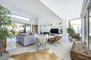 A spacious living area with a sofa, a coffee table, a TV, and a large window. - Vila Camilo Ponta do Farol by CoolHouses (Lagos)