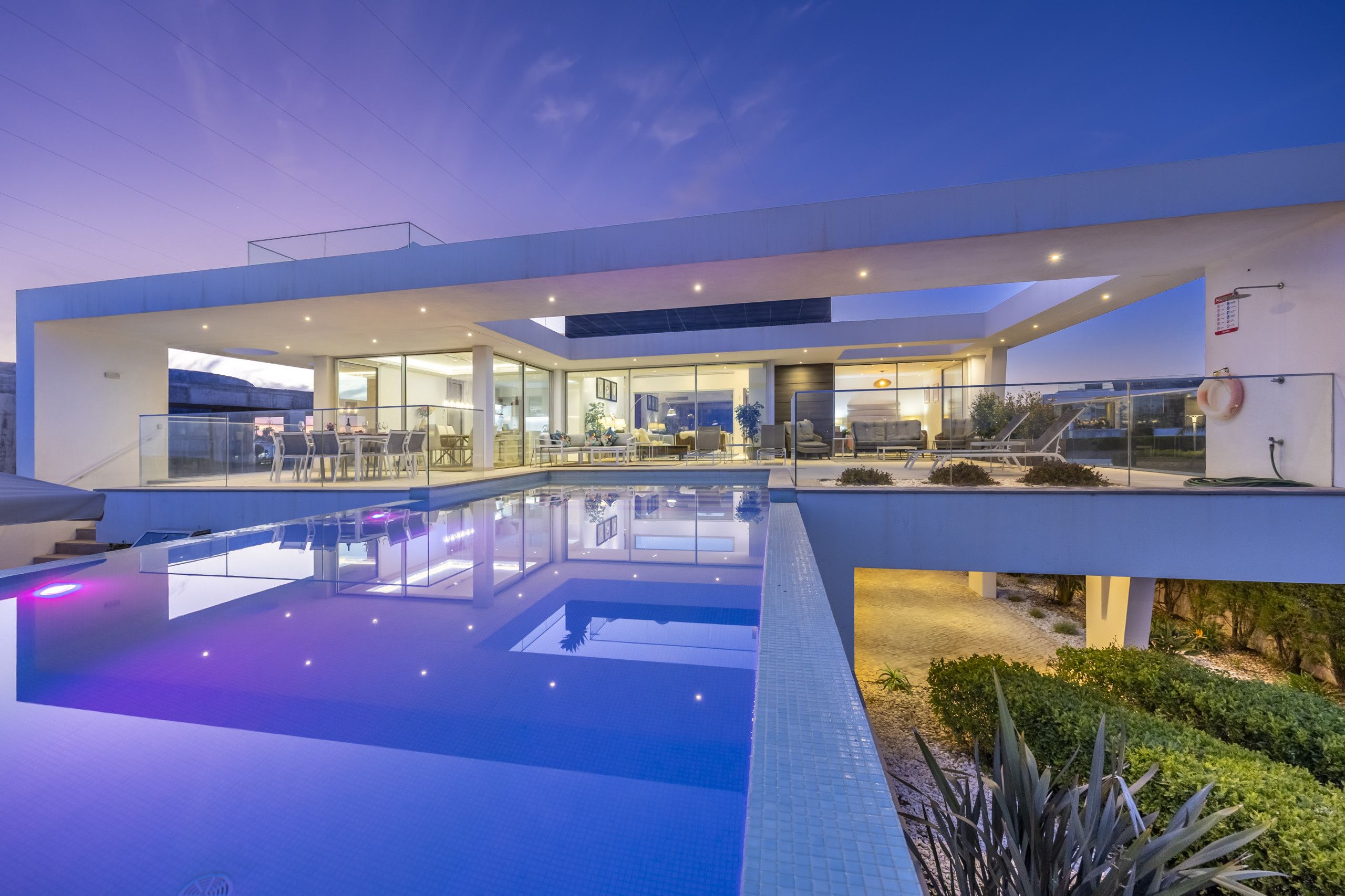 A modern building with a glass facade, a swimming pool, and outdoor seating.