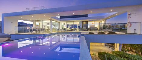 A modern building with a glass facade, a swimming pool, and outdoor seating.