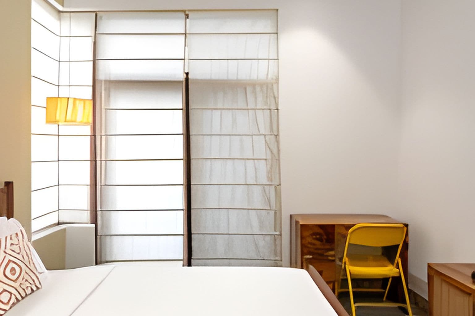 A bedroom with a bed, a chair, a desk, and a wardrobe with sliding doors.