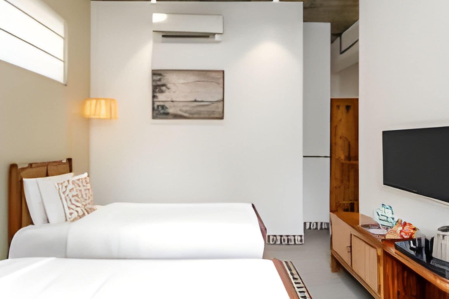 Habitación de hotel con cama, escritorio con televisor de pantalla plana, armario y un cuadro en la pared.