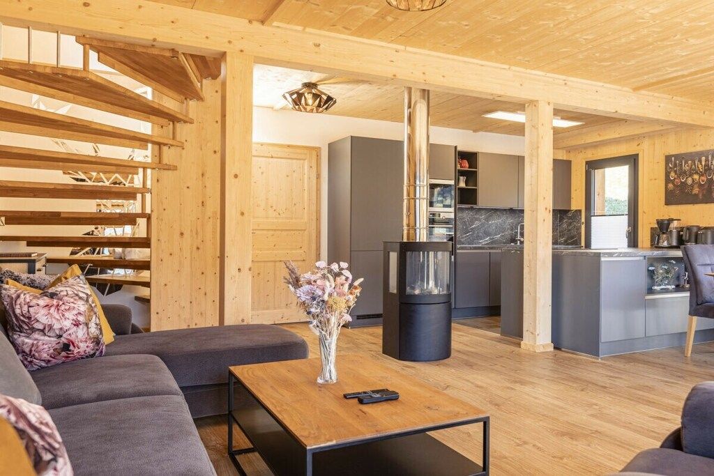 A modern interior with a wooden ceiling, a sofa, a coffee table, and a kitchen area.