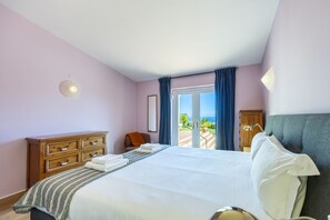 Een hotelkamer met een bed, een houten dressoir, een stoel en uitzicht op het groen.
