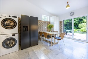 A modern kitchen with a built-in washer, a refrigerator, and a dining area with a table and chairs. - Quinta da Belavista 55 by CoolHouses (Luz)