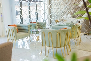 A modern living room with a glass coffee table, sofas, and chairs with gold legs.