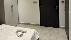 Ein Schlafzimmer mit einem Bett, einem Kleiderschrank, einer Tür und einem Lichtschalter an der Wand.