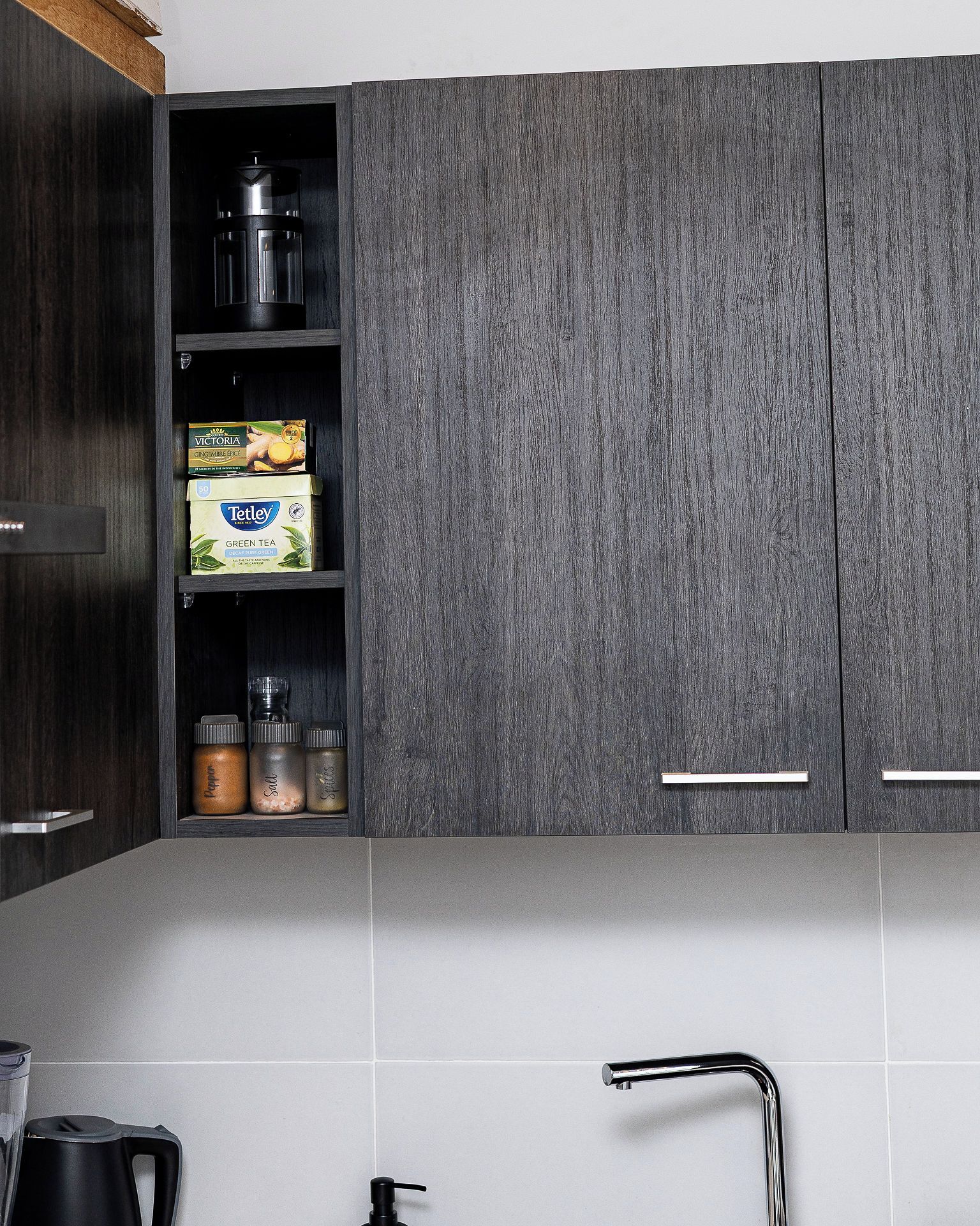 Una cocina con armarios de madera oscura, un hervidor de acero inoxidable y una cafetera.