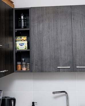 Una cocina con armarios de madera oscura, un hervidor de acero inoxidable y una cafetera.