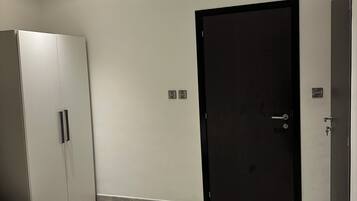 Un dormitorio con una cama, un armario, una puerta y un interruptor de luz en la pared.